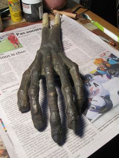 an image of a dirty hand on top of news paper with paintbrushes and glue