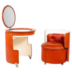 an orange chair and mirror on wheels with a white table in the middle, and a brown leather ottoman sitting next to it