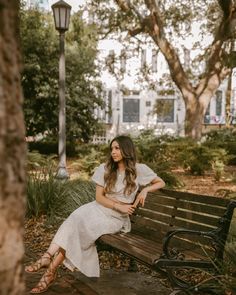 a woman sitting on top of a wooden bench