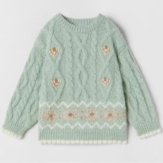 a green sweater with gold and white designs on it