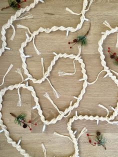 several pieces of white rope with pine cones and berries attached to them on a wooden floor