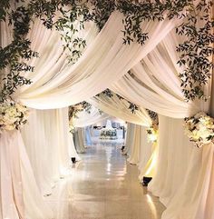 an aisle decorated with white drapes and flowers