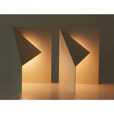 two lamps that are sitting next to each other on a table, one is shaped like an upside down triangle