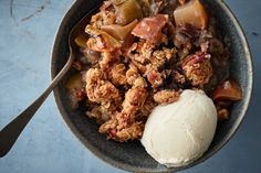 a bowl filled with fruit and ice cream on top of a blue tablecloth next to a spoon