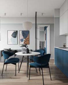 a dining room table with blue chairs and artwork on the wall in the back ground