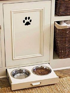 a dog's food bowl and water dish in front of a white cabinet with paw prints on it