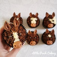 cupcakes made to look like farm animals are being held by someone's hand