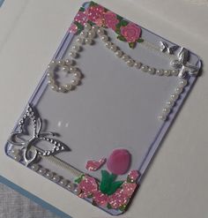 a card with flowers and pearls on the edges, attached to a string of beads