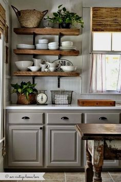 a kitchen with gray cabinets and shelves filled with dishes