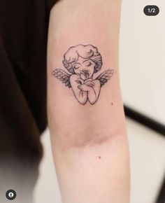 a small tattoo on the arm of a girl with an angel holding her hands together