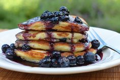 a stack of pancakes with blueberries and syrup