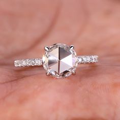 a close up of a person's hand holding an engagement ring with a diamond on it