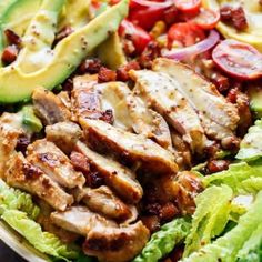 a salad with chicken, lettuce, tomatoes and avocado