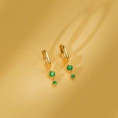 Emmy Add a touch of vibrant color to your ear stack with these solid gold huggies and two natural emerald drop stones. These versatile earrings effortlessly elevate your everyday look or add a touch of modern elegance to special occasions. Choose from classic yellow, sleek white, or romantic rose gold to complement your style. - Handmade- Solid Gold- Natural Emerald - Total Emerald Carat Weight: 0.30 ctw- Huggies Dimensions: Outer 11 mm, Inner 8.5 mm- Drop Length: 9 mm * Sold as a pair * All pie Yellow Gold Emerald Huggie Earrings, Green Gemstone Huggie Earrings, Elegant Green Dangle Huggie Earrings, Ear Stack, Handmade Fine Jewelry, Romantic Roses, White Gift Boxes, Natural Emerald, Gold Set