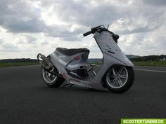 a scooter is parked on the side of the road with cloudy skies in the background