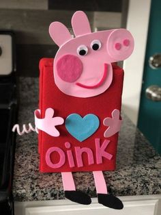 a pink pig is standing on top of a red book with the word oink written in it