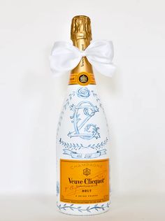 a bottle of wine with a white bow on it's top and gold cap