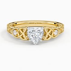 a yellow gold ring with a heart shaped diamond in the center and two diamonds on each side