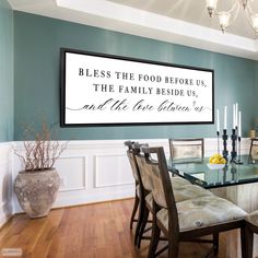 a dining room table and chairs in front of a framed sign that says, blessing the food before us