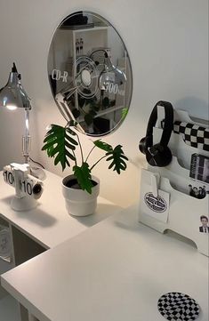 a white desk topped with a mirror next to a potted plant