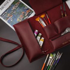 the contents of a red leather purse are neatly organized and ready to be used as art supplies