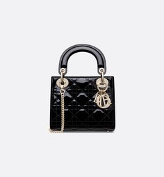 The Lady Dior bag epitomizes the House's vision of elegance and beauty. Sleek and refined, the timeless style is crafted in black patent calfskin with Cannage stitching, creating the legendary and instantly recognizable quilted texture, while pale gold-finish metal D.I.O.R. charms further embellish its silhouette. Featuring a removable chain strap, the miniature Lady Dior bag can be carried by hand or crossbody as an ideal evening wear companion.. Dior Mini Bag, Lady Dior Mini, Mini Lady Dior, Lady Dior Handbag, Dior And I, Womens Designer Bags, Small Lady, Christian Dior Couture, Dior Handbags