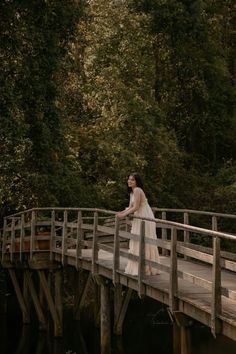 a bride and groom standing on a wooden bridge