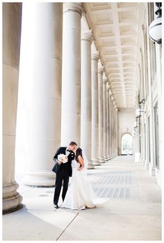 a bride and groom kissing in front of columns