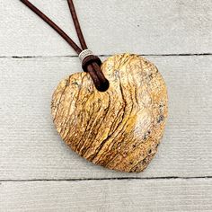 Beautiful Picture Jasper pendant on a rustic brown leather cord. The Picture jasper stone is in the shape of a heart and has gorgeous colors of brown and tan.  Accented with a stamped silver bead and a rustic brown leather cord. The necklace is finished with a Tiger Eye bead and loop closure. Necklace length: 32 inches (58cm) Pendant Size: 48 x 50mm (2 x 2 inches) The necklace is ready for shipping and will be shipped within 24-72 hours from purchase. The necklace will arrive in a gift box with Earthy Brown Waxed Cord Necklaces, Earthy Brown Waxed Cord Necklace, Brown Waxed Cord Necklace For Gift, Adjustable Brown Jewelry With Heart Charm, Rustic Brown Jewelry With Adjustable Cord, Brown Adjustable Cord Jewelry For Healing, Rustic Brown Waxed Cord Necklace, Rustic Brown Pendant Jewelry, Bohemian Brown Heart-shaped Jewelry