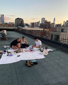 three people sitting on top of a roof next to each other eating food and condiments