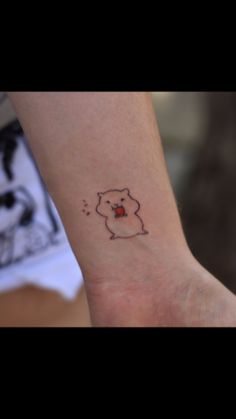 a small tattoo on the wrist of a person's arm, with a bear holding an apple in its mouth