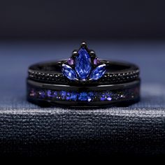 two black rings with blue and purple stones on them, one has a leaf shaped diamond in the center