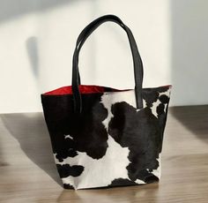 This Black and White Leather Tote Bag Is Made from 100% natural calf hide and full grain leather. The black and white hair-on calfskin leather is a striking combination, paired with black leather accents and a soft fabric lining. With one main pocket and two extra pockets (one with a zipper), this bag is both stylish and practical. Features : Dimensions: 12" high, 18" wide, 6.5" deep; 24" handle Material: Genuine hair-on calfskin leather and full grain leather Colors: Black and white calfskin, black leather Lining: Soft fabric Shipping Information - Free shipping is available for all orders within the continental United States (48 states). - For orders shipping to Hawaii, Alaska, APO's, and US territories, please contact us for a shipping quote before placing your order. - Worldwide shippi Ladies Work Bag, Womens Work Bag, Handmade Leather Tote Bag, Carry On Tote, Leather Accessories Handmade, Leather Colors, Work Tote Bag, Work Tote, Travel Work