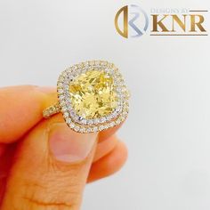 a person holding a yellow diamond ring in their hand with the words design & knr on it