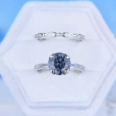 an engagement ring with a blue diamond in it on top of a white display case