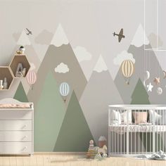 a baby's room with mountains, hot air balloons and a crib in the foreground