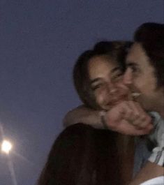 two people are hugging each other in front of a street light and the moon behind them