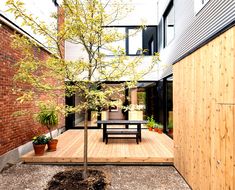 an outdoor area with wooden decking, potted trees and benches on the ground