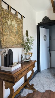 a wooden table sitting in front of a painting on the wall next to a doorway