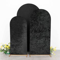 two black tombstones sitting next to each other on a wooden table with flowers in the background