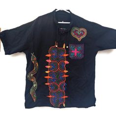 Peruvian Unisex T-Shirt, Meticulously Hand-Embroidered Amidst The Lush Jungle Canopy. Each Stitch Tells A Story Of Ancient Traditions And Vibrant Culture, Making Each Piece A Unique Work Of Art. Adorned With A Charming Pocket On The Right Side And A Captivating Heart-Shaped Snake Motif, This Shirt Perfectly Combines Style With Sustainability, Made With Love And Care By Skilled Artisans. This T-Shirt Is Handmade By Peruvian Amazon Jungle Artisans. Measure Length 30 Broad 24 Shoulder 18 Black Embroidered Crew Neck Top, Black Floral Embroidery Crew Neck T-shirt, Embroidered Short Sleeve Shirt With Relaxed Fit, Black Embroidered T-shirt For Summer, Traditional Black Embroidered Shirt, Relaxed Fit Multicolor Embroidered Tops, Black Bohemian T-shirt For Festival, Black Long Sleeve Embroidered T-shirt, Summer T-shirt With Multicolor Embroidery