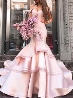 a woman standing in front of a building wearing a pink dress with flowers on it