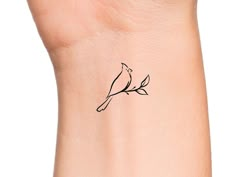 a small bird tattoo on the wrist is shown in black ink, and it has a branch