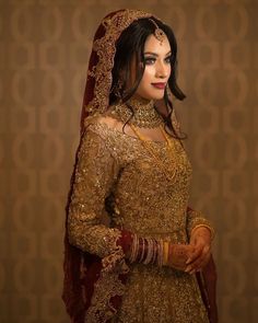 a woman in a gold and red bridal gown with an elaborate veil on her head