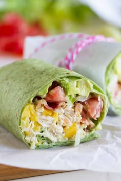 a wrap filled with meat and veggies on top of paper