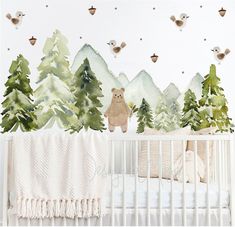 a baby's crib with trees and mountains painted on the wall behind it