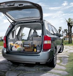 the back end of a silver minivan with its trunk open and food in it