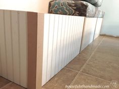 a couch sitting on top of a tiled floor next to a white wall and wooden paneling