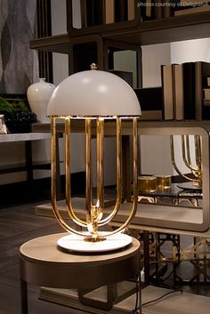 a table lamp sitting on top of a wooden table next to a shelf filled with books