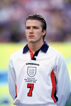 a male soccer player is standing on the field with his head turned to the side